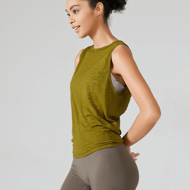 Woman wearing a lightweight green sporty tank top with cut on back, perfect for exercise. Made from breathable cotton, nylon, and spandex.